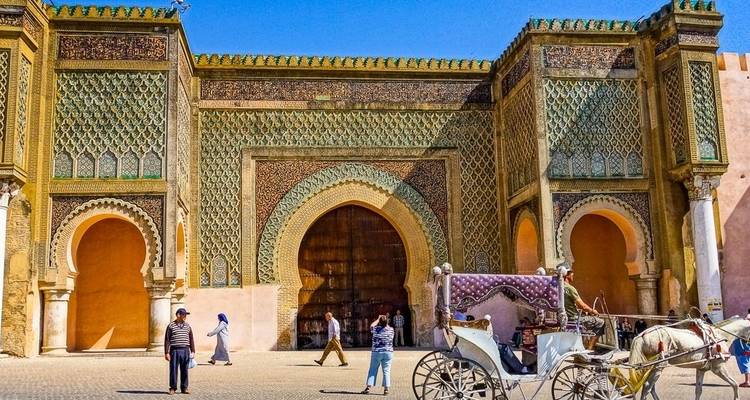 Historisches Stadttor mit Menschen und einer Pferdekutsche.