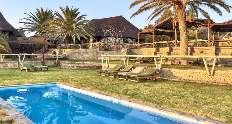 Ein Resort mit Palmen, einem Pool und Lounge-Bereichen.