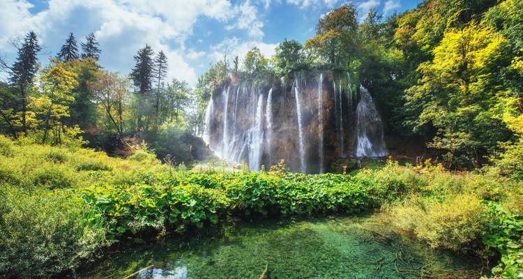 Mächtiger Wasserfall, der über üppige Klippen in kristallklare Seen im Nationalpark Plitvicer Seen stürzt.
