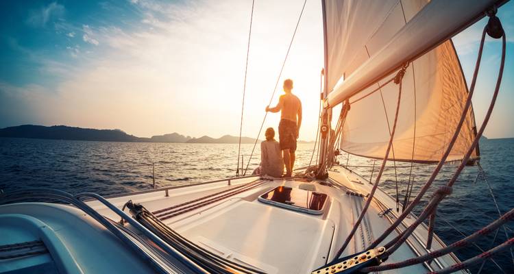 Junges Paar genießt den Sonnenuntergang während einer Segelfahrt mit einer Yacht über die ruhigen Gewässer der Adria.