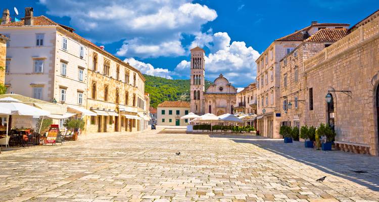 Großzügiger Steinplatz, gesäumt von historischen Gebäuden und Außencafés unter einem strahlend blauen Himmel auf der Insel Hvar.