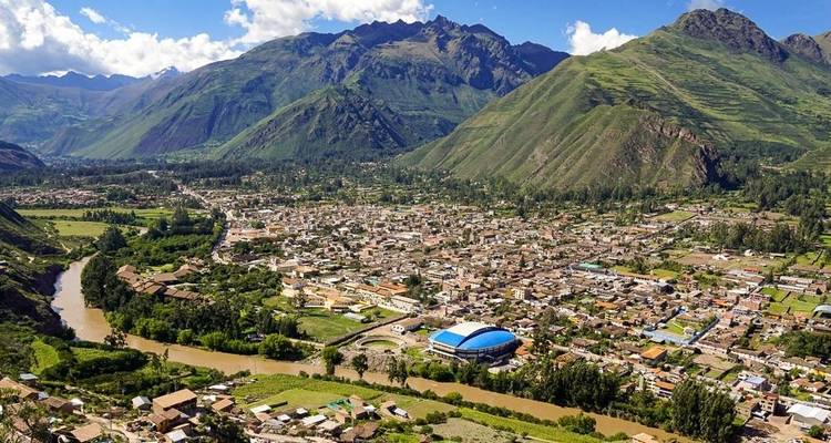 Luchtfoto van een stad met omliggende bergen en een rivier.