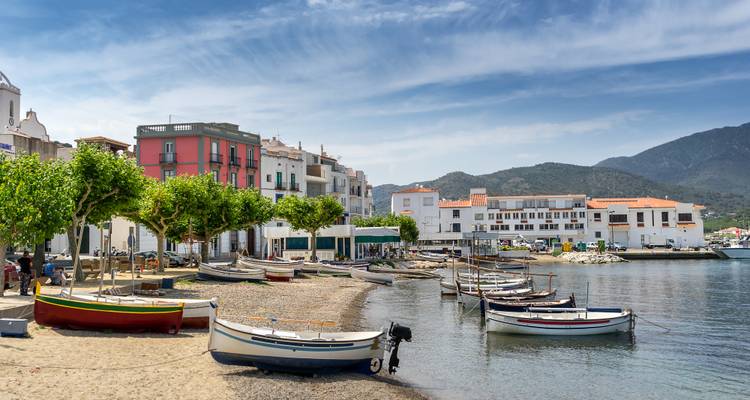 Charmant village de pêcheurs méditerranéen au bord de l'eau avec des bateaux colorés, une plage de galets et des maisons blanchies à la chaux.