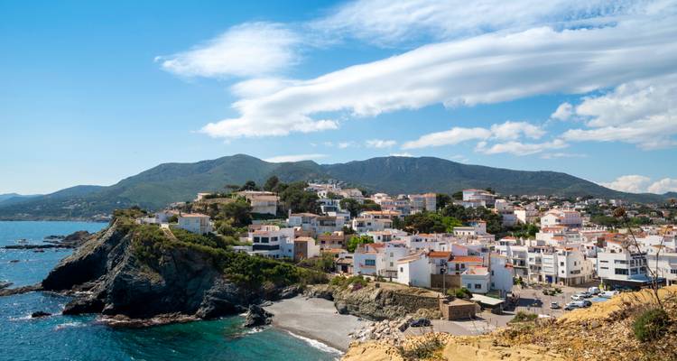 Village côtier panoramique aux toits en terre cuite perché sur un cap rocheux face à la mer Méditerranée d'un bleu éclatant.