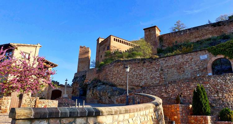 Forteresse médiévale et remparts sous un ciel dégagé avec un sentier au premier plan.