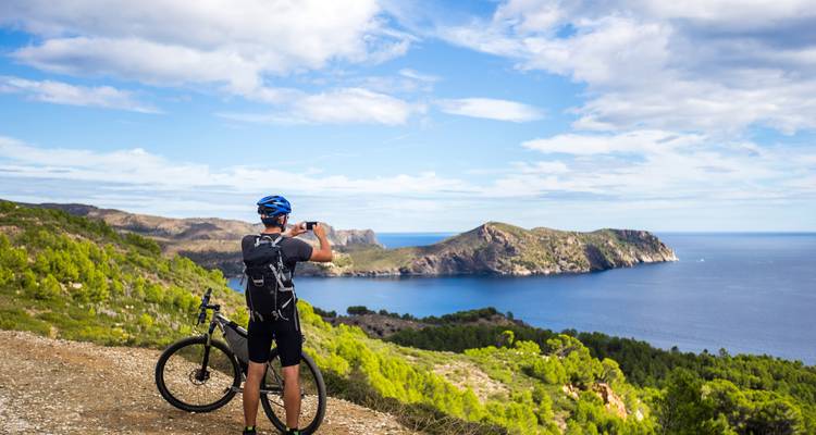 Radfahrer macht ein malerisches Foto mit Blick auf Küstenklippen.