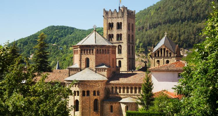 Historisches Steingebäude mit einem Turm, umgeben von Grünflächen.