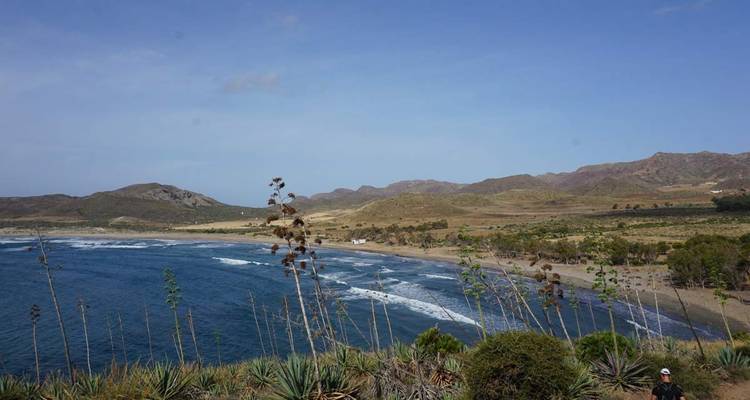 Vue de plage côtière avec des montagnes à l'arrière-plan.