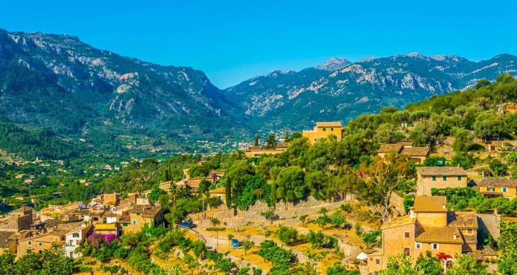 Vue panoramique d'un village niché dans une vallée entourée de montagnes.