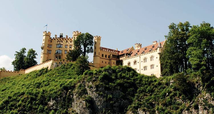 Château sur une colline entouré d'une végétation luxuriante.
