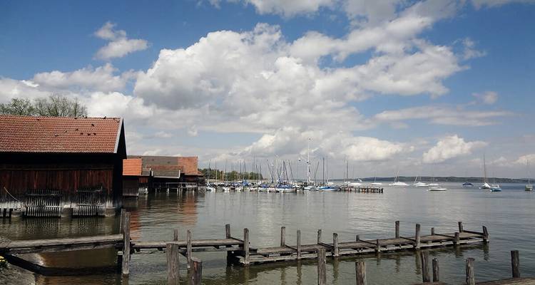 Bateaux amarrés dans une marina paisible au bord d'un lac sous les nuages.