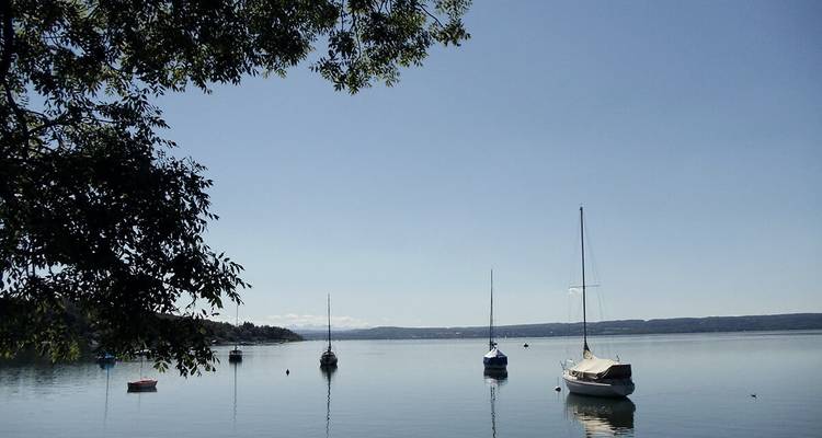 Petits voiliers flottant sur un lac calme sous un ciel clair.