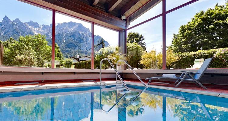 Piscine intérieure avec vue sur la montagne depuis la fenêtre.