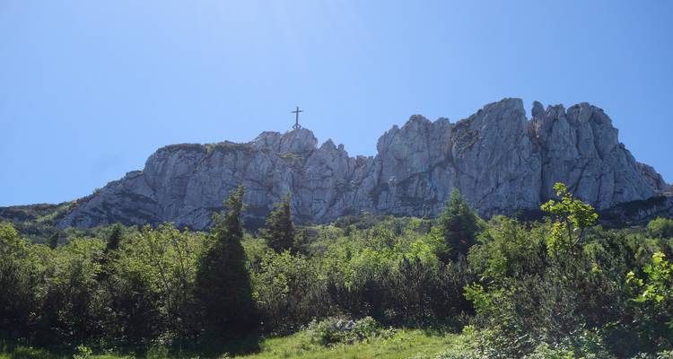 A rocky mountain with a large cross at the peak.