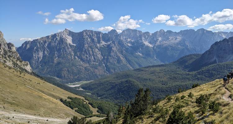 Wanderer, die durch ein Tal mit weitläufigen Ausblicken gehen.