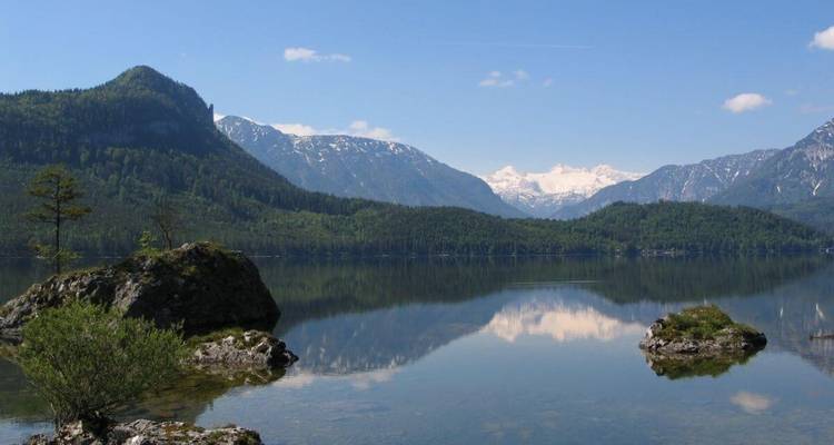 Lac limpide avec reflet de montagne et un arrière-plan de montagnes enneigées.