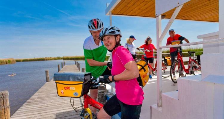 Radfahrer stehen an einem Dock mit Blick auf das Wasser.