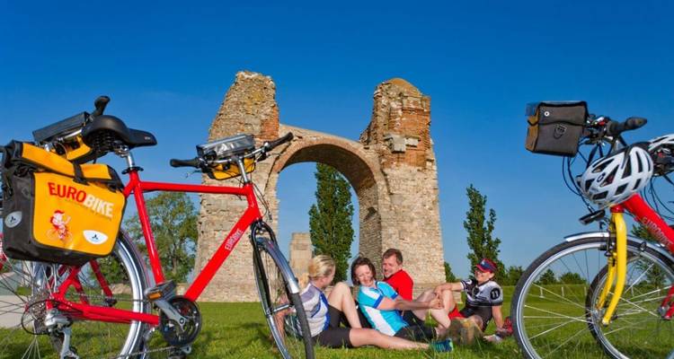Gruppe von Menschen mit Fahrrädern bei historischen Ruinen.