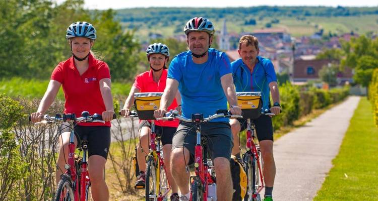 Menschen, die auf einem Weg mit einer malerischen Kulisse aus Hügeln und Grün radeln.