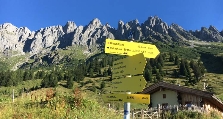 Berglandschaft mit Wegschildern, die in verschiedene Richtungen zeigen.