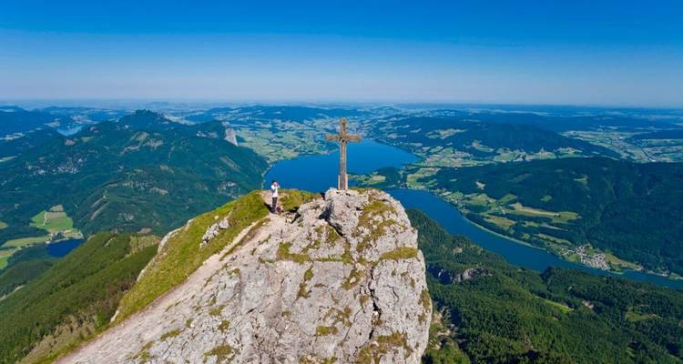 Une personne debout sur un sommet de montagne avec une vue panoramique derrière.