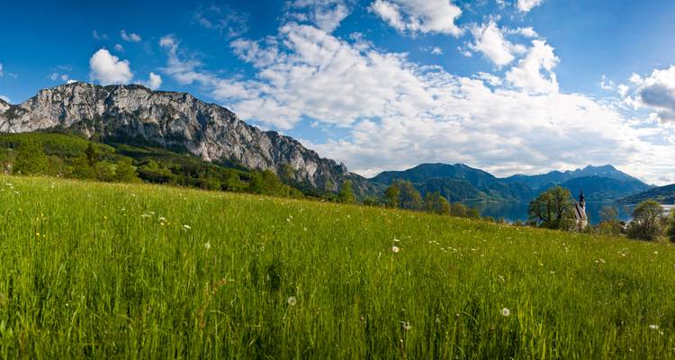 Panoramic view of a field with mountains and a lake in the background.