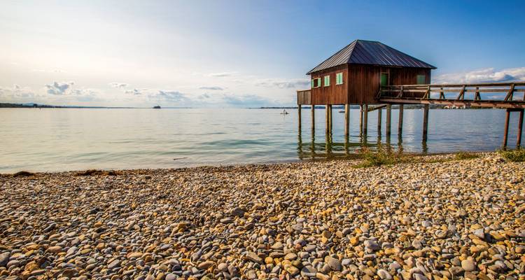 Casa sobre pilotes en la orilla del lago bajo un cielo despejado.