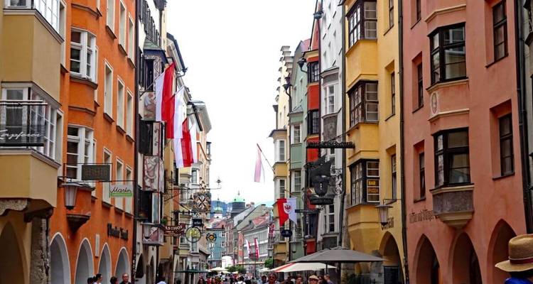Rue animée de la ville avec des bâtiments colorés et des cafés en terrasse.