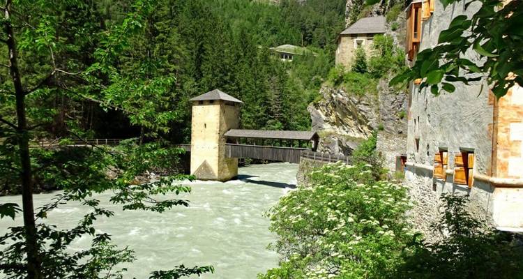 Pont historique enjambant une rivière puissante bordée de falaises boisées.