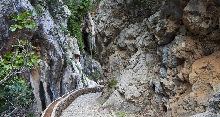 Un étroit sentier de pierre à travers des formations rocheuses escarpées.