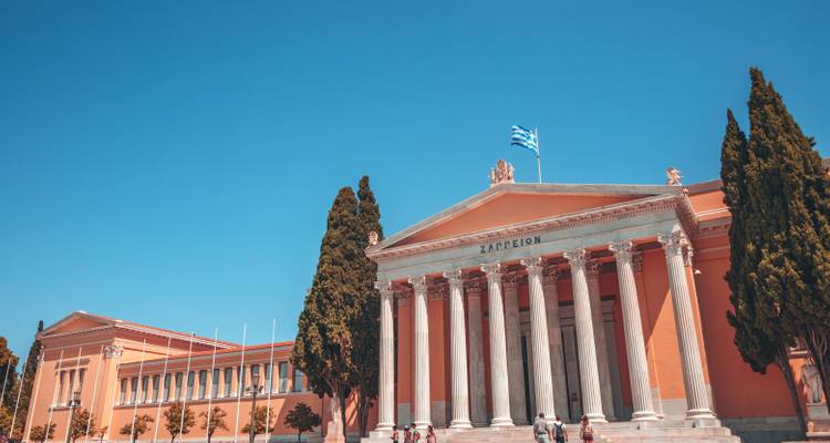 Zappeion Exhibition Hall with Greek flag and blue sky.