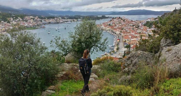 Une personne regardant au loin un port avec des bateaux et un environnement montagneux.