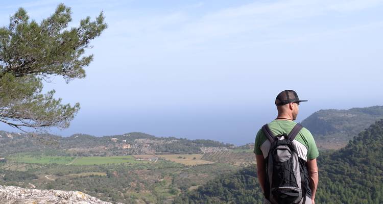 Un homme avec un sac à dos regardant un paysage vers la mer.