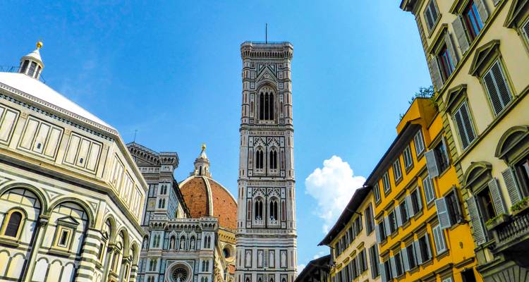 Nahaufnahme der Skyline von Florenz mit der Kathedralenkuppel, dem Baptisterium und dem schlanken Glockenturm, die in einen strahlend blauen Himmel ragen.