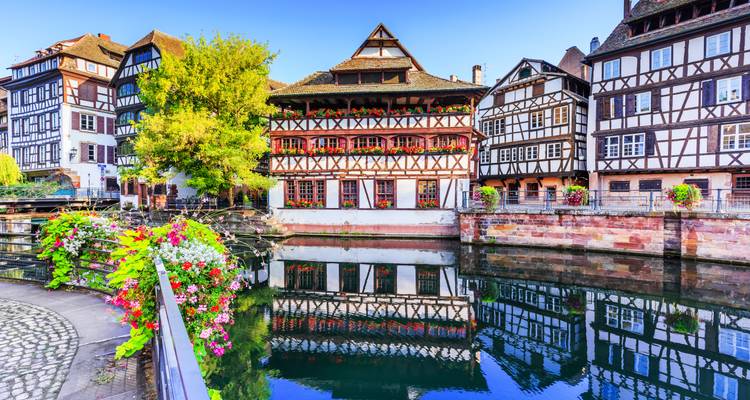 Bâtiments pittoresques à colombages le long d'un canal avec des fleurs colorées.