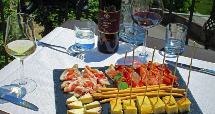 Table dressée avec verres à vin, bouteille de vin et assortiment de nourriture.
