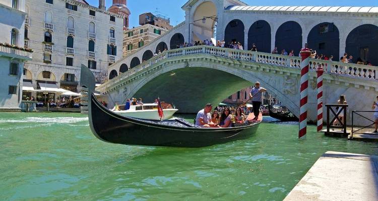Paseo en góndola bajo un puente histórico en Venecia.