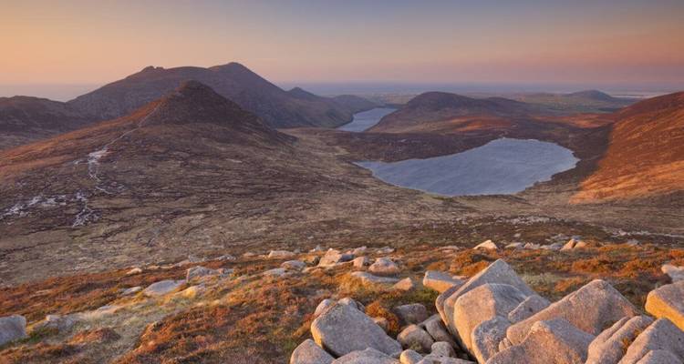 Amanecer dorado sobre los picos escarpados y los lagos gemelos de las Montañas de Mourne.