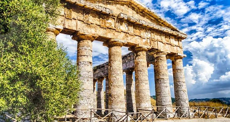 Antiker Tempel mit Säulen vor blauem Himmel.
