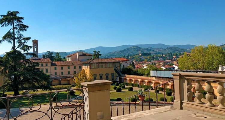 Vue d'une ville avec des bâtiments aux toits rouges et des collines au loin.