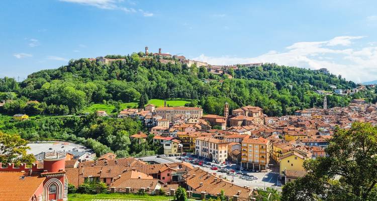 Pintoresco pueblo italiano en una colina with techos de terracota anidado en exuberantes colinas verdes en un día soleado.