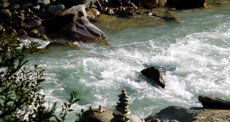 Ruisseau de montagne rocheuse avec de petits cairns au bord de l'eau.