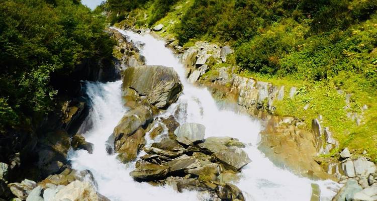Une cascade qui dévale au milieu d'un terrain rocheux et d'une végétation verdoyante.