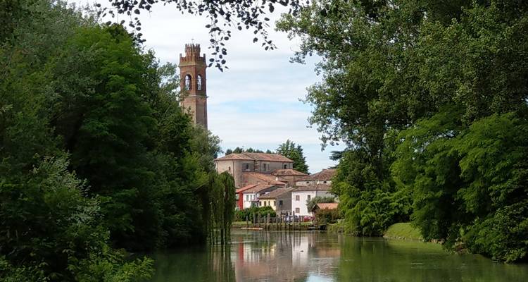 Idyllisches Dorf mit einer Kirche nahe einem Fluss.