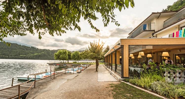 Ein Uferweg mit Tretbooten und einem charmanten Gebäude.