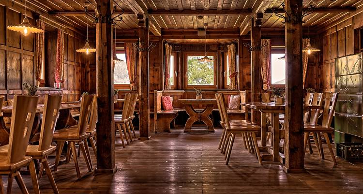 Amplio comedor rústico con mesas de madera, sillas e iluminación cálida.