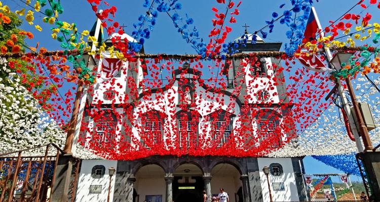 Decoraciones callejeras coloridas con un festival frente a un edificio histórico.