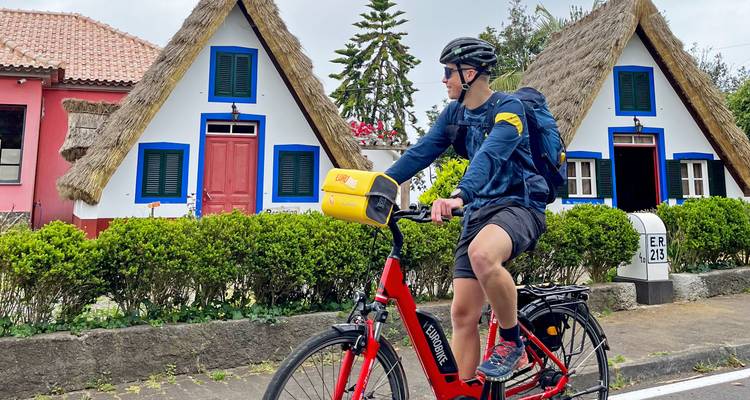 Ciclista pasando frente a casas triangulares tradicionales.