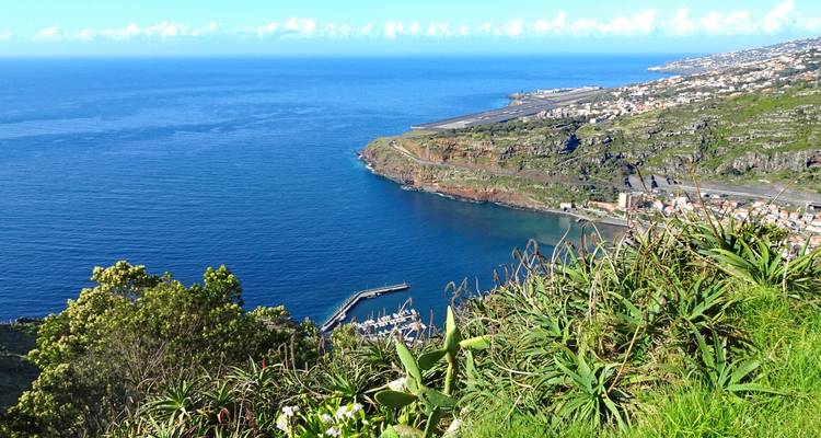 Vista aérea de un pueblo costero y marina con mar azul.