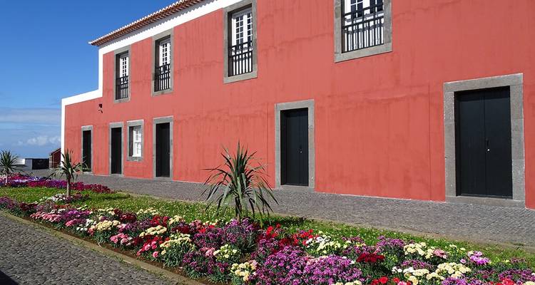Edificio rojo con jardín de flores coloridas.